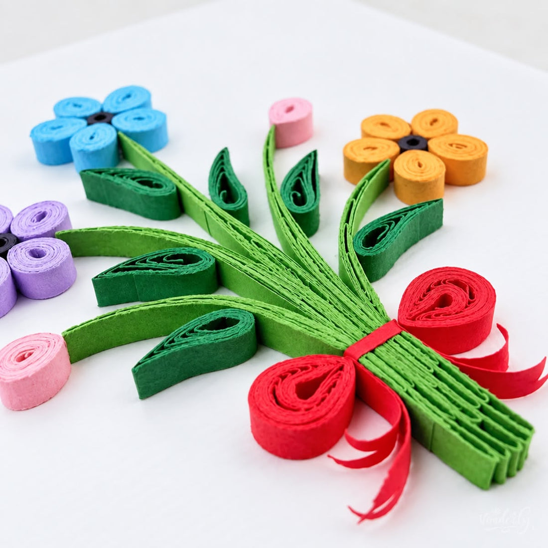 Bouquet quilled greeting card with blue, purple, and orange paper flowers on green stems tied with a red bow.