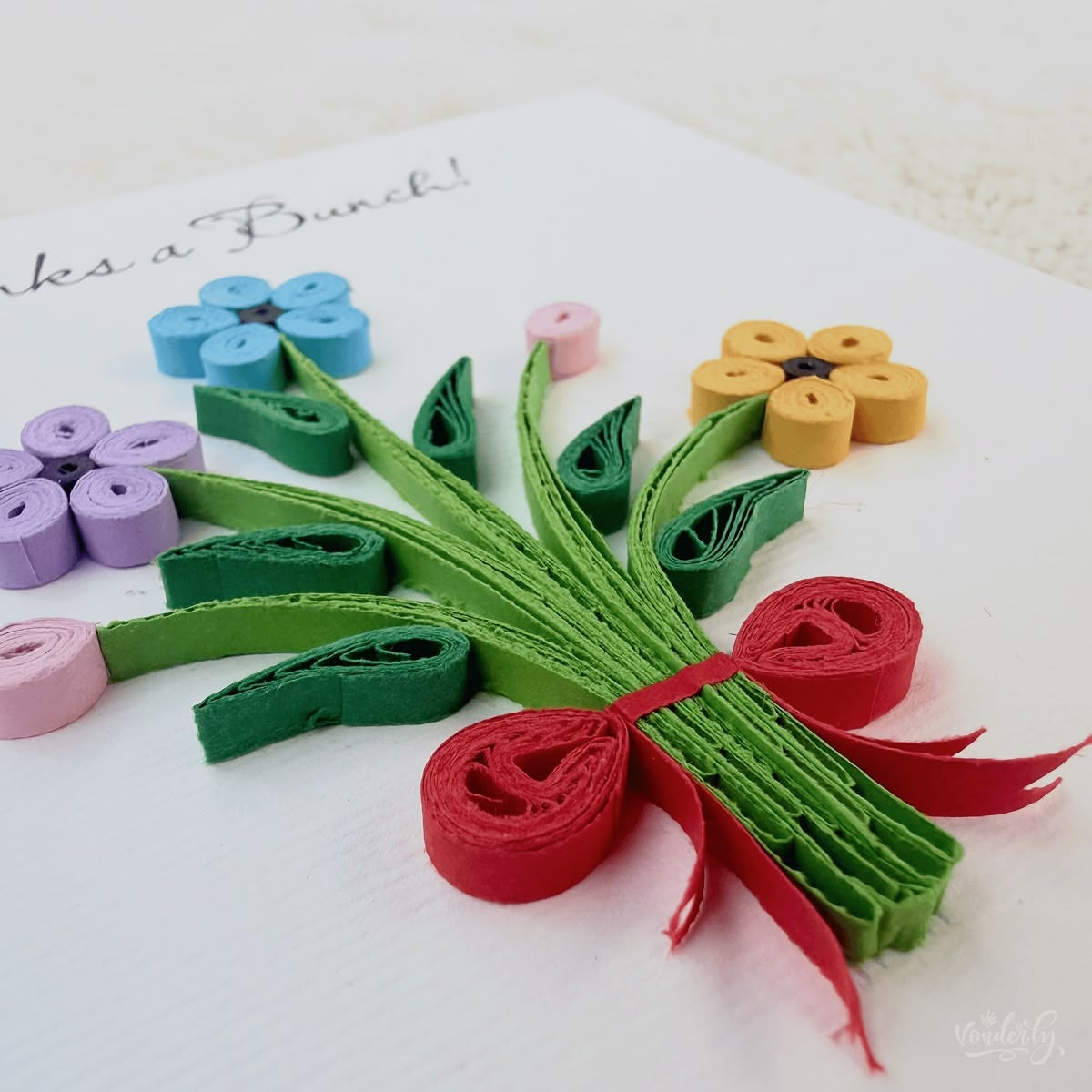 Angled view of quilled thank you bouquet card showing 3D raised paper art, gathered stems with red ribbon bow visible