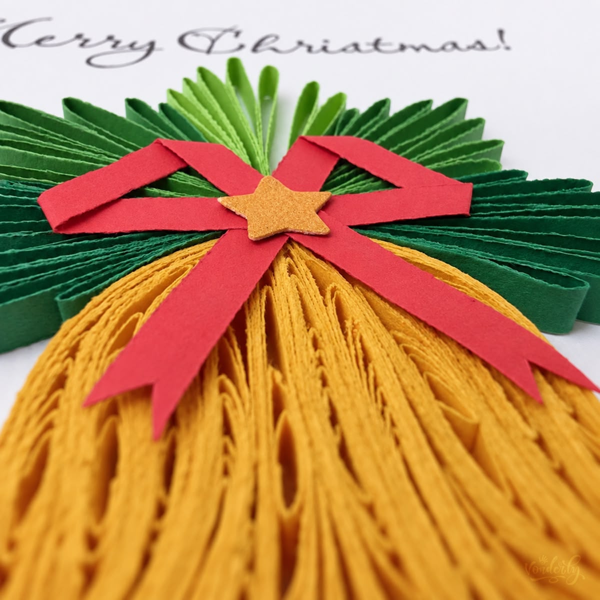 Close-up of gold paper strips looped into a bell beneath a red bow and gold star.