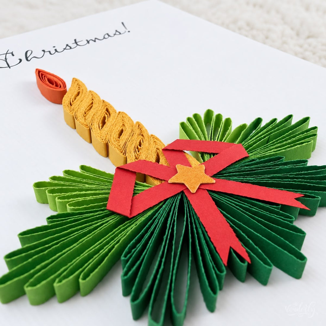 Quilled Christmas card with a gold paper candle, orange flame, green pine, and a red bow.