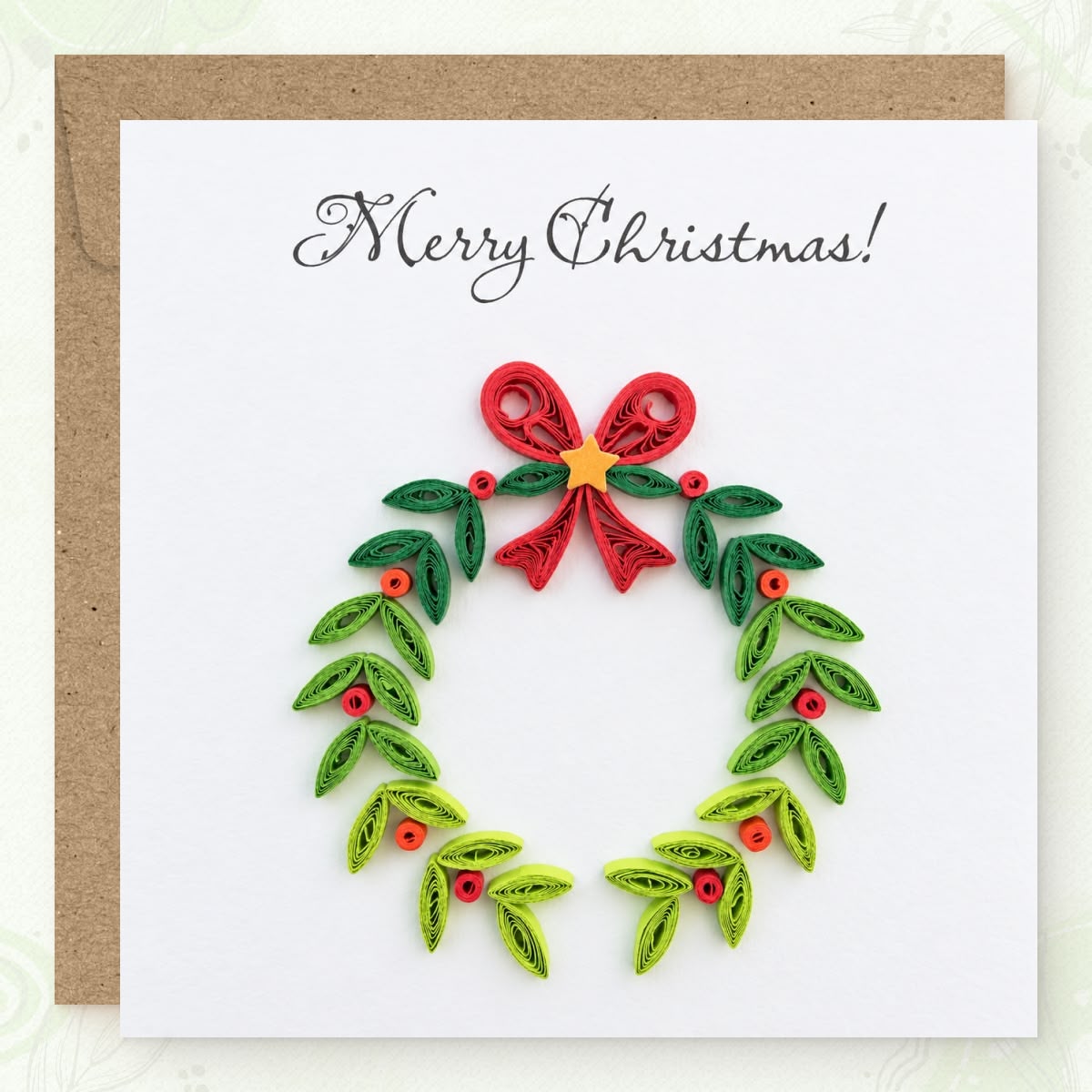 Quilled Christmas card with a green paper wreath, red berries, and a red bow.