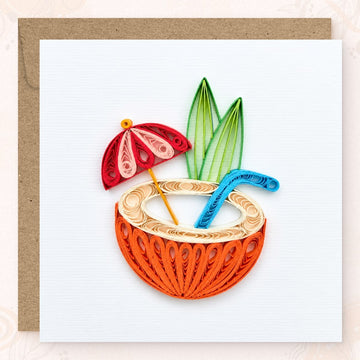 Quilled greeting card with an orange paper coconut drink, red cocktail umbrella, and blue straw.