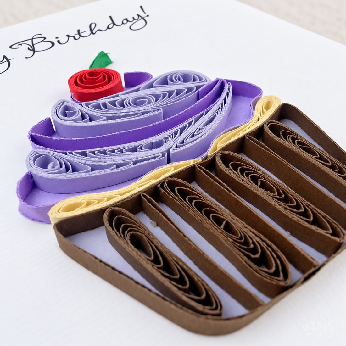 Quilled birthday card with a purple paper frosting swirl, red cherry, and striped wrapper.
