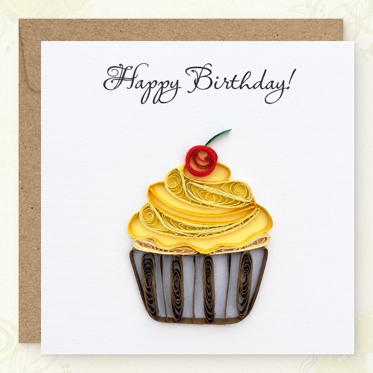 Quilled birthday card with a yellow paper frosting swirl, red cherry, and striped wrapper.