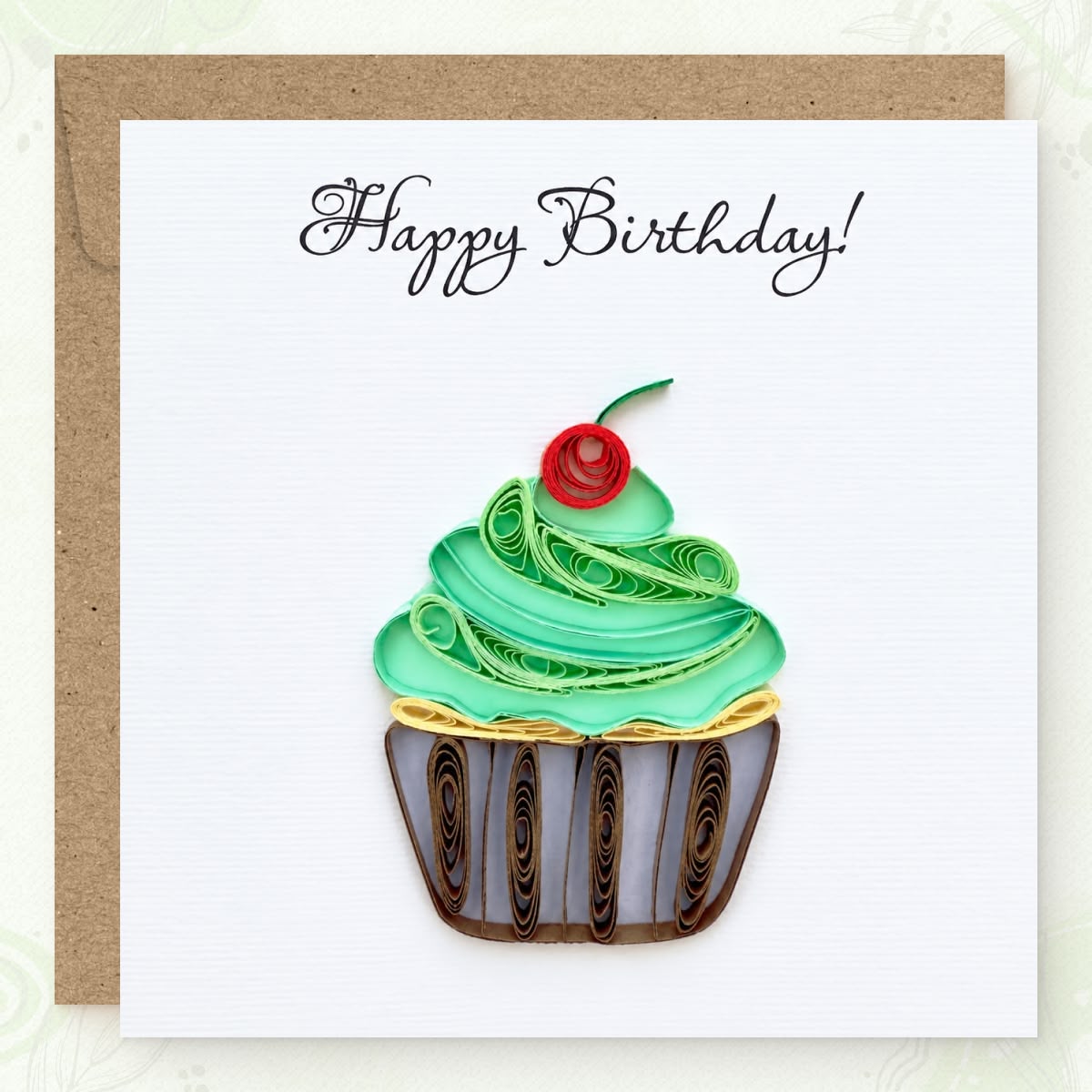 Quilled birthday card with a green paper frosting swirl, red cherry, and striped wrapper.
