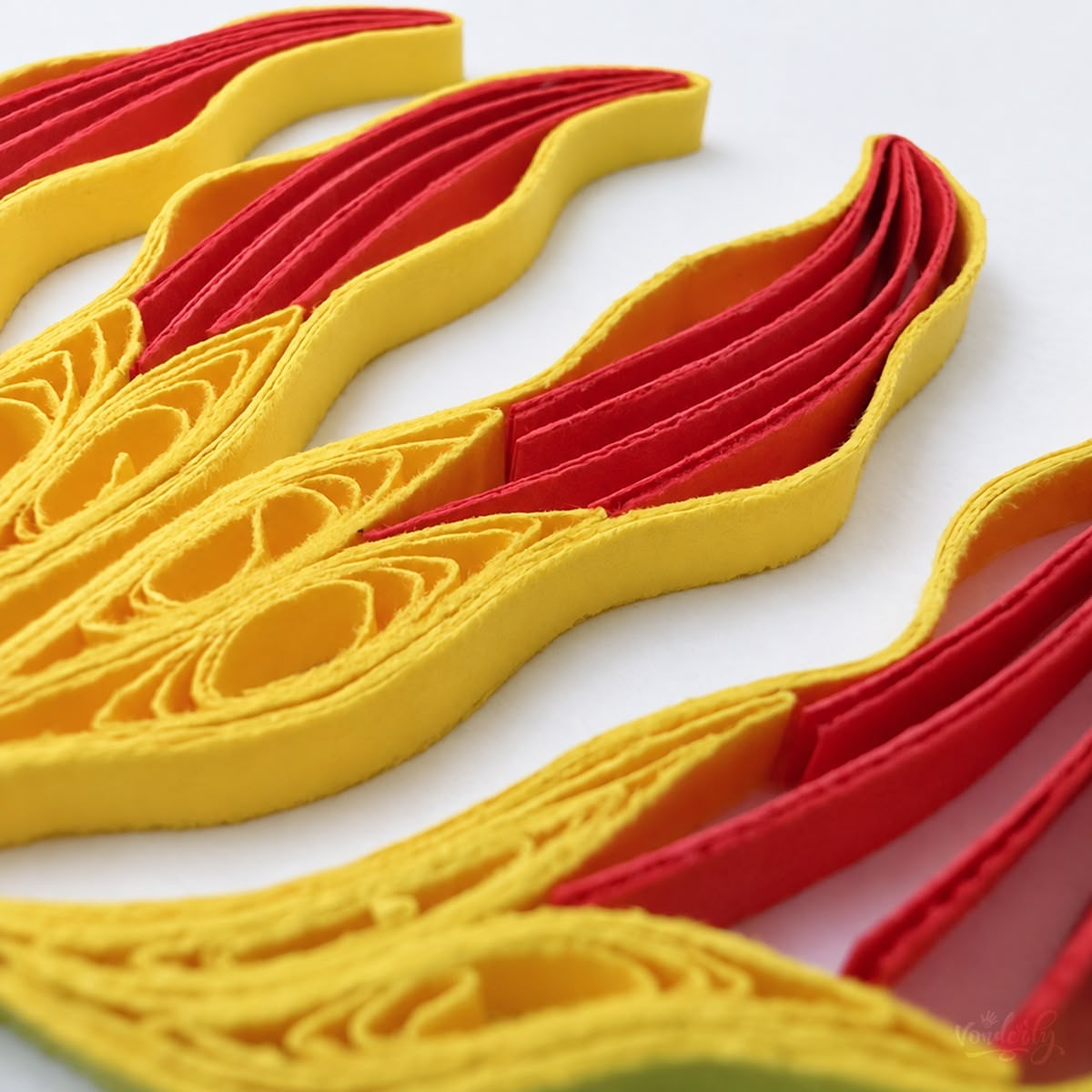 Close-up of coral pink and yellow paper strips set on edge inside the Flame Lily petals.