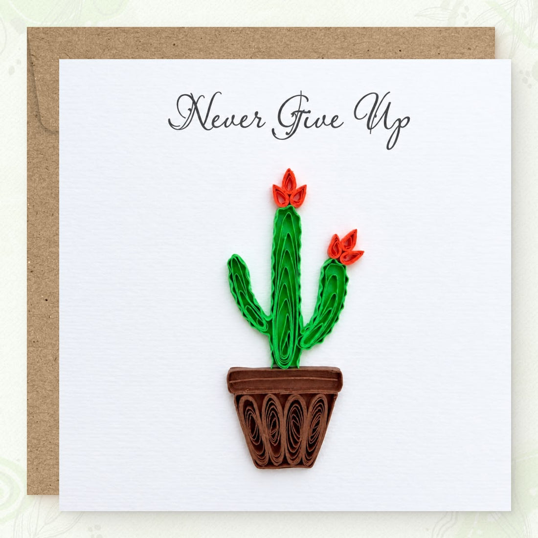 Flowering Cactus quilled greeting card with a green paper cactus, two orange blooms, and a brown pot, printed "Never Give Up" above.