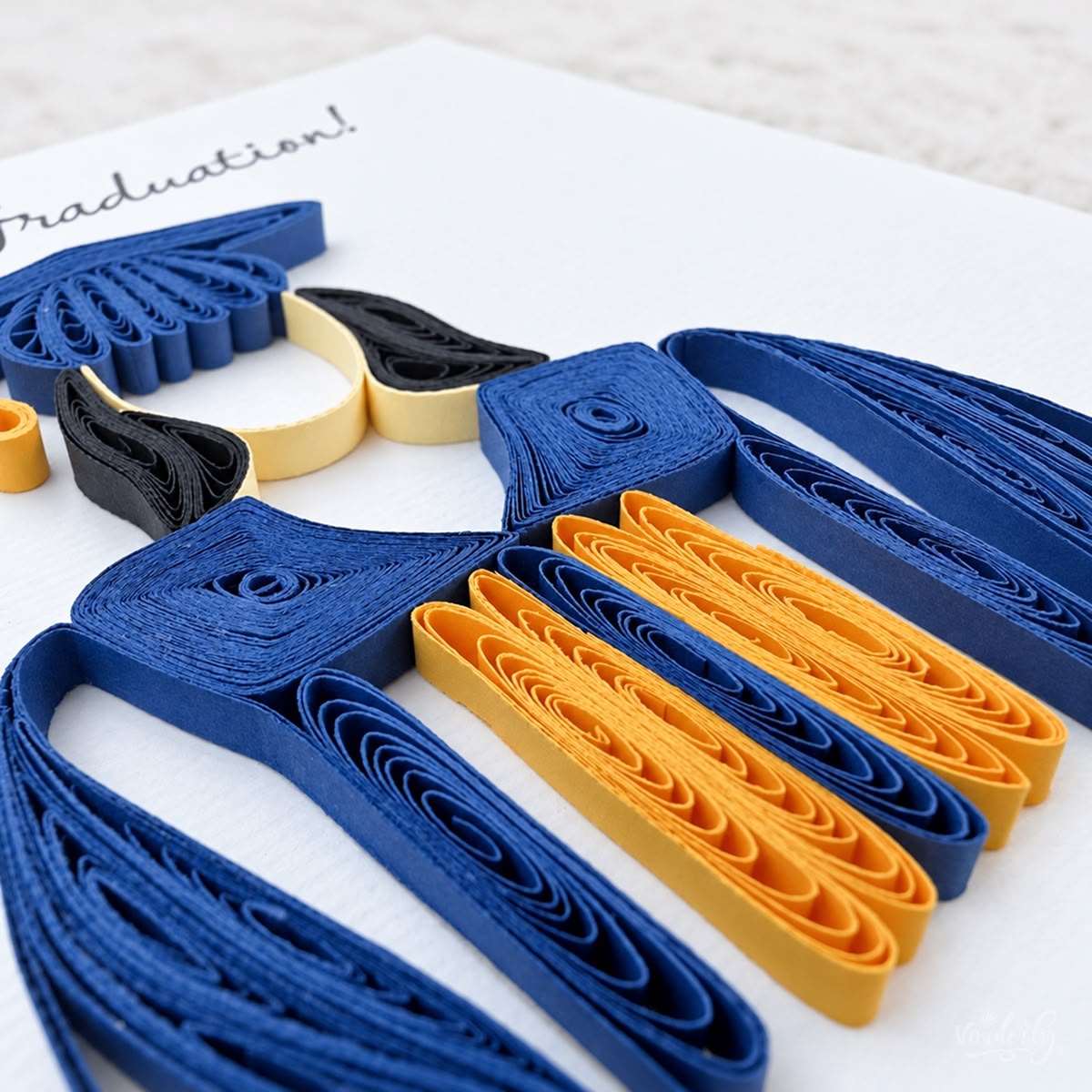 Angled view of the graduation card showing the raised navy gown strips and the gold stole.