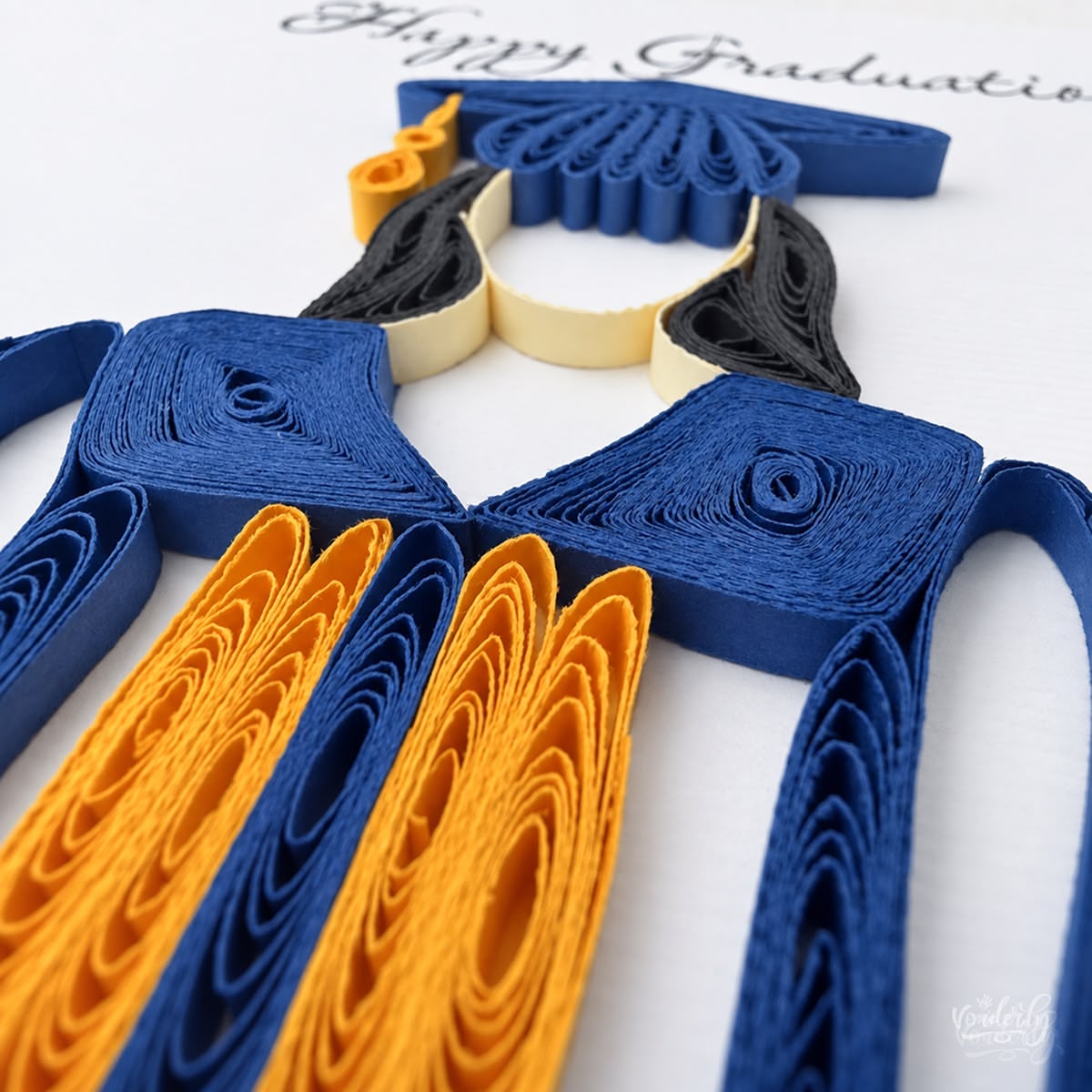 Close-up of navy and gold paper strips set on edge forming the collar and stole of the graduate.