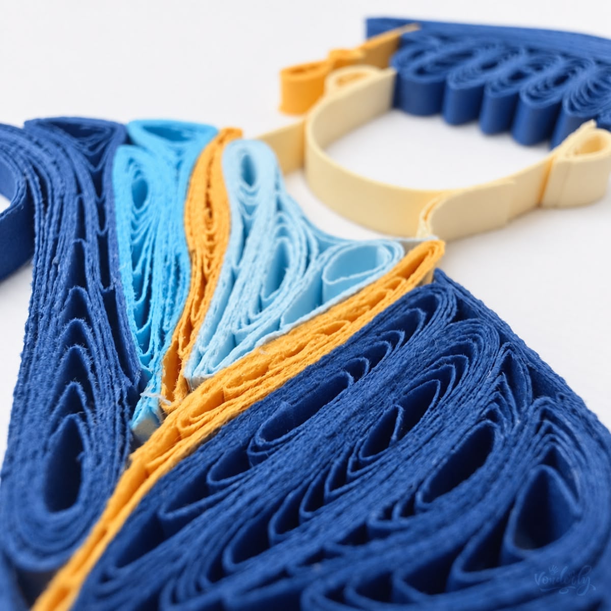 Close-up of navy, sky blue, and gold paper strips set on edge forming the graduate's hood.