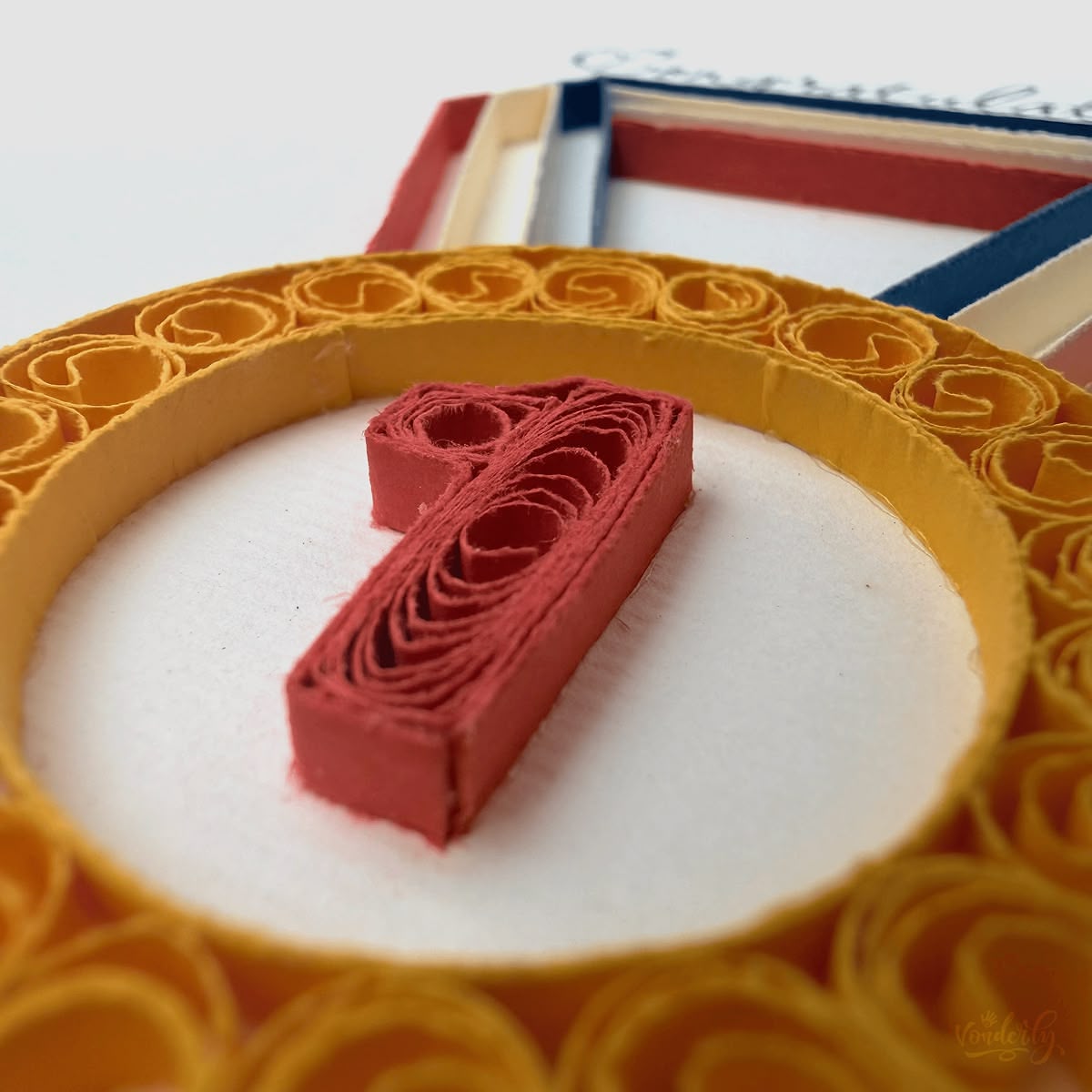 Close-up macro of paper quilling on congratulations medal card, multiple tightly rolled and chained gold coils forming the medal ring and red number 1 detail