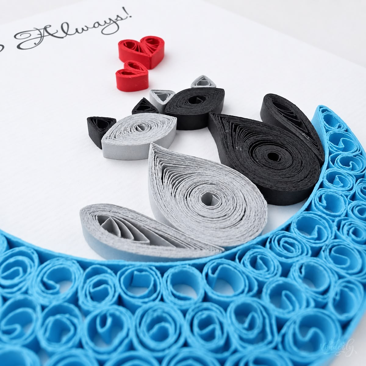 Close-up of gray and black paper teardrops forming the two cats, with red quilled hearts alongside.