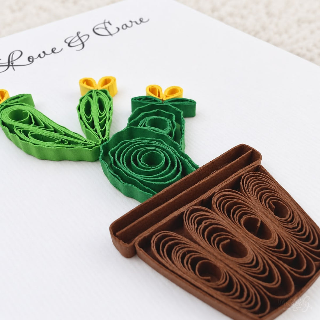 Prickly Pear quilled greeting card with green paper cactus pads, three yellow blooms, and a brown pot, printed "With Love & Care" above.