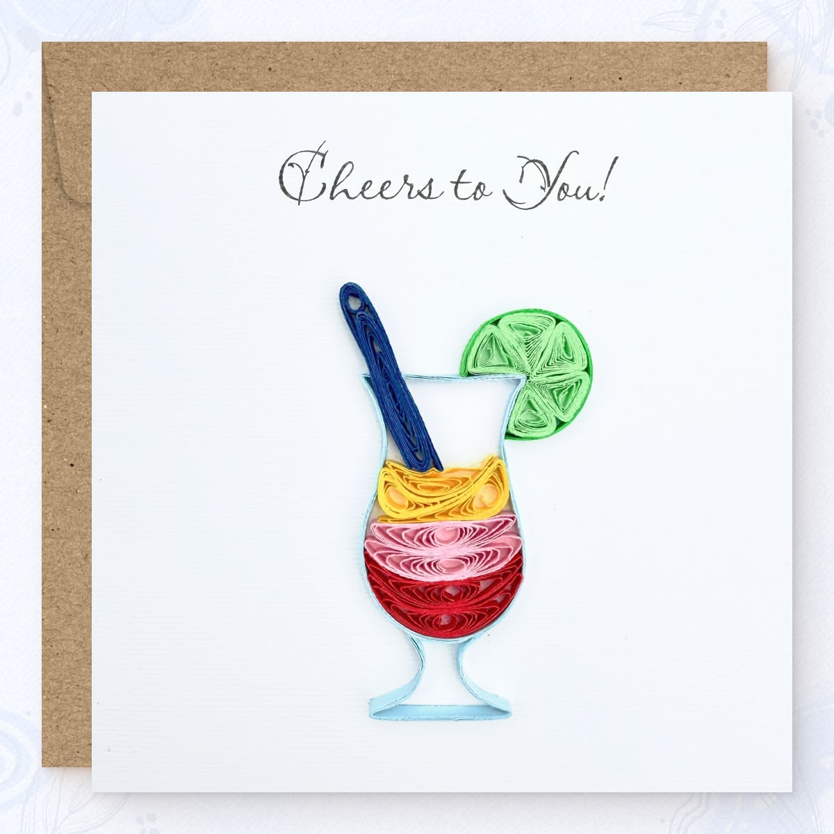 Handmade quilled congratulations greeting card showing a layered cocktail in red, pink, and gold with a navy swizzle stick and green lime wheel, "Cheers to You" printed in calligraphic script, paper art by Vonderly