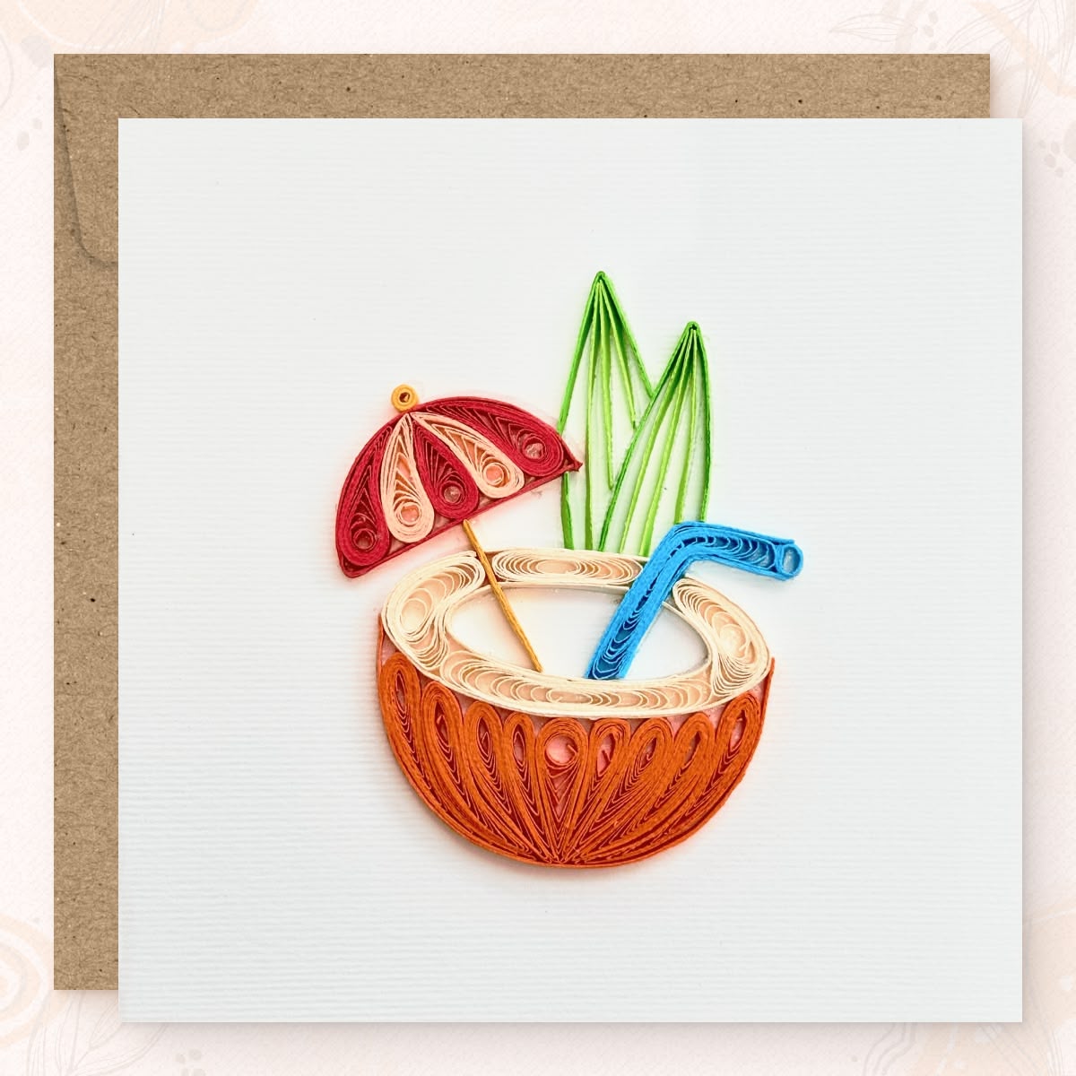 Handmade quilled tropical greeting card showing a halved orange coconut with a cream drink, red and pink cocktail umbrella, blue straw, and green leaves, paper art by Vonderly