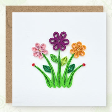 Handmade quilled flower greeting card, three flowers (pink, purple, and yellow) on long curved green stems with leaves in three shades of green, paper art by Vonderly