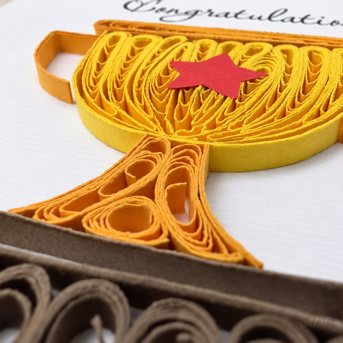 Close-up of yellow paper strips looped and fanned across the trophy bowl beside a red star.